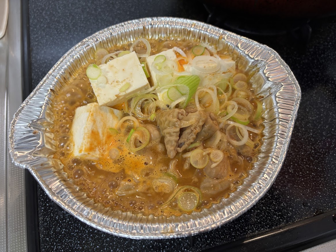 じっくり仕上げた柔らか煮込み もつ煮込み鍋に豆腐や刻みネギ追加して煮込み