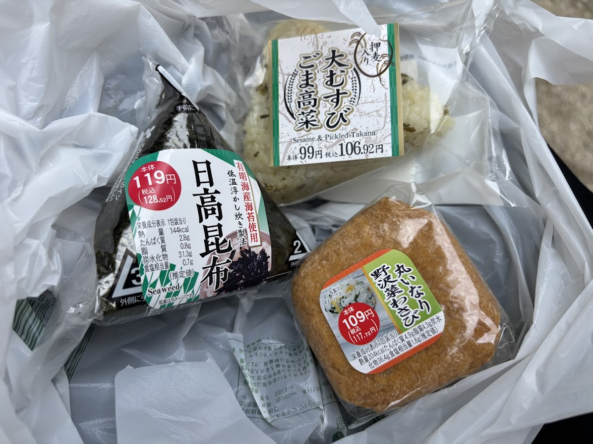 まいばすけっと 広尾5丁目店で買ったおにぎり3個(日高昆布おにぎり(119円)、押麦入り 大むすび ごま高菜(106円)、丸いなり野沢菜わさび(109円税抜)に、グリーンアイ オーガニック濃い緑茶。袋入れて452円(税込)