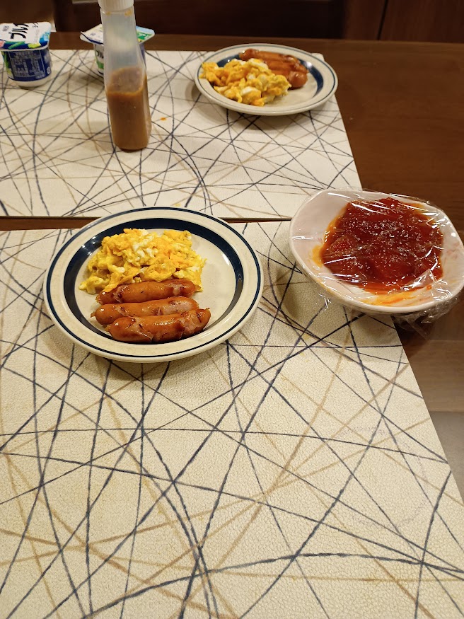 実家の朝飯 おかずにスクランブルエッグ、ウインナー、筋子、ヨーグルト、謎のソース