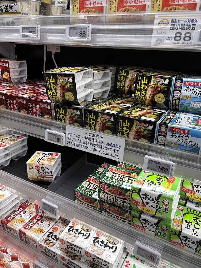 いなげや花小金井駅前店の納豆売り場で「タカノメカー様の商品は現在、出荷調整がかかっている為、商品の供給が不安定になっています。欠品する事がありますので、ご了承程、宜しくお願い致します。」