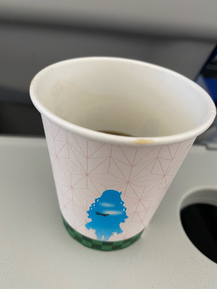 航空機内でコーヒー（鬼滅の刃の紙コップ）