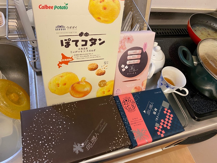 買って来たお土産のカルビー ぽてコタン、石屋製菓 美冬 さくらともも、白い恋人ブラック、白い恋人×福岡 「博多すきっちゃん」（白い恋人のホワイトチョコレートをあまおう苺ラング・ド・シャでサンド）